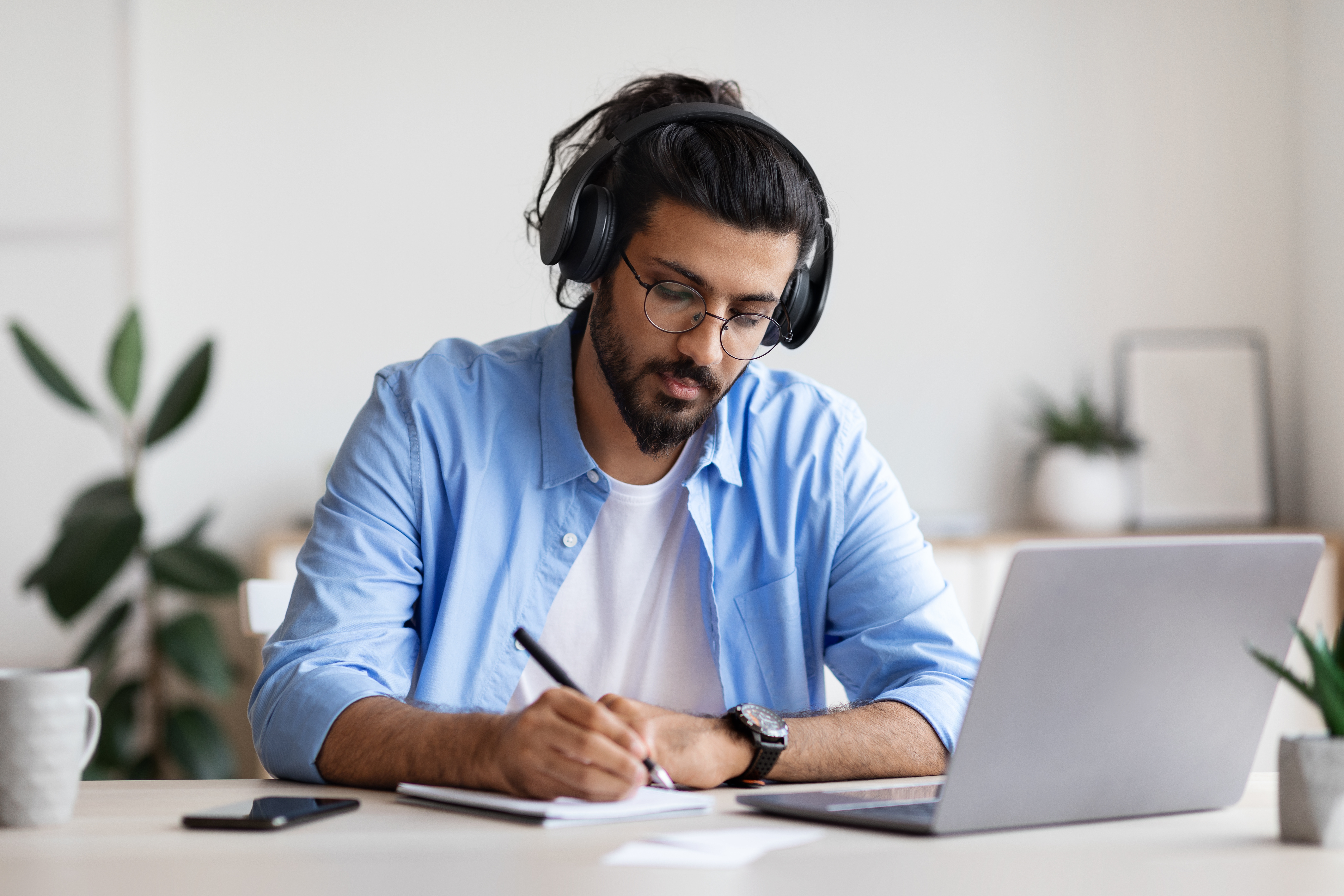 Young man studying with laptop at home with headphones on