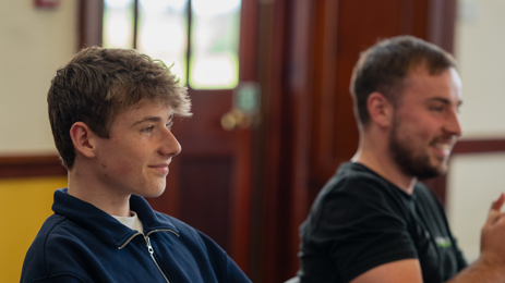 Two members of the Youth Advisory Forum sitting at a table, listening.