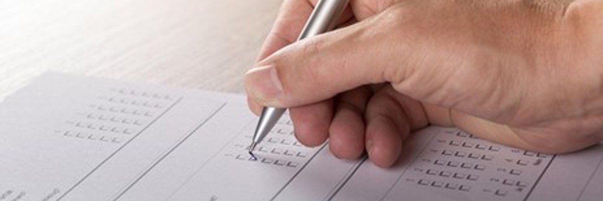 A pen in hand filling out a paper questionnaire