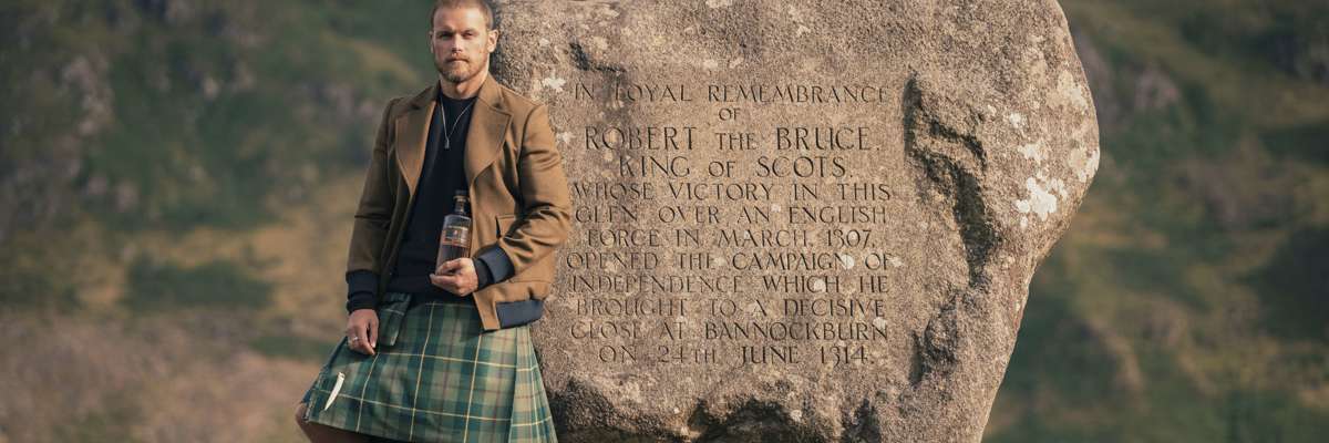 Sam Heughan standing against rock 
