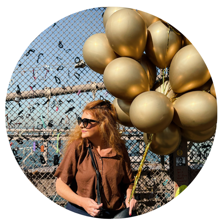 Image of a woman looking to the side holding gold balloons.